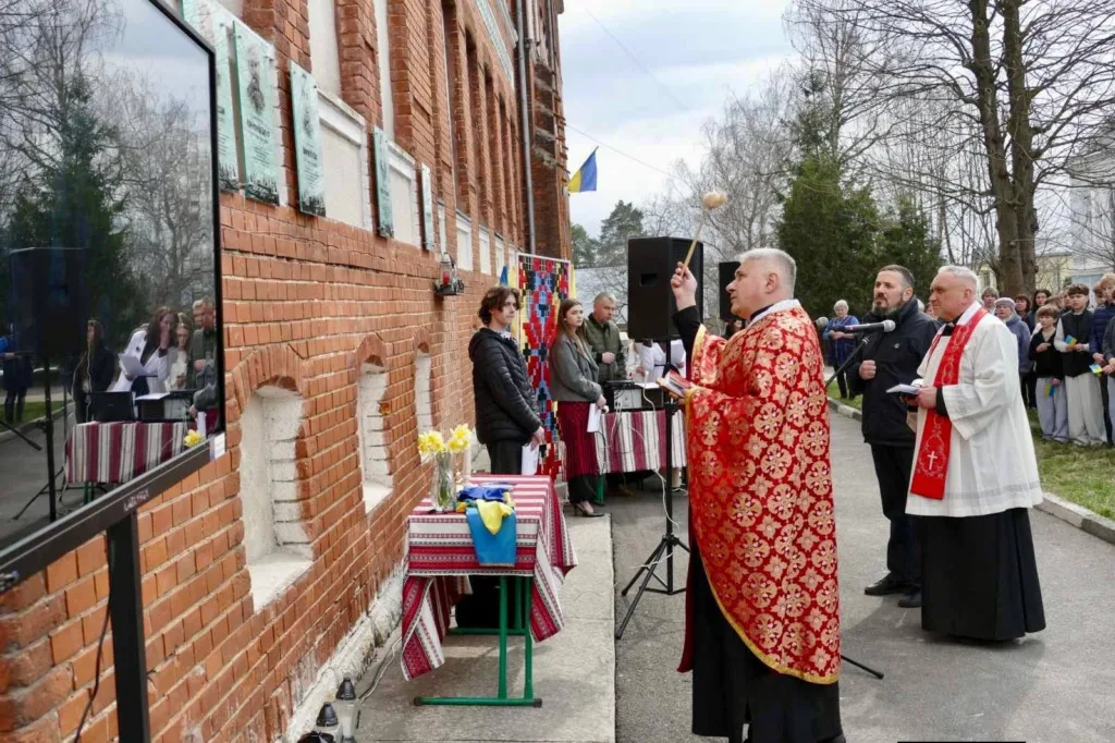 Священник освячує пам’ятну дошку біля школи