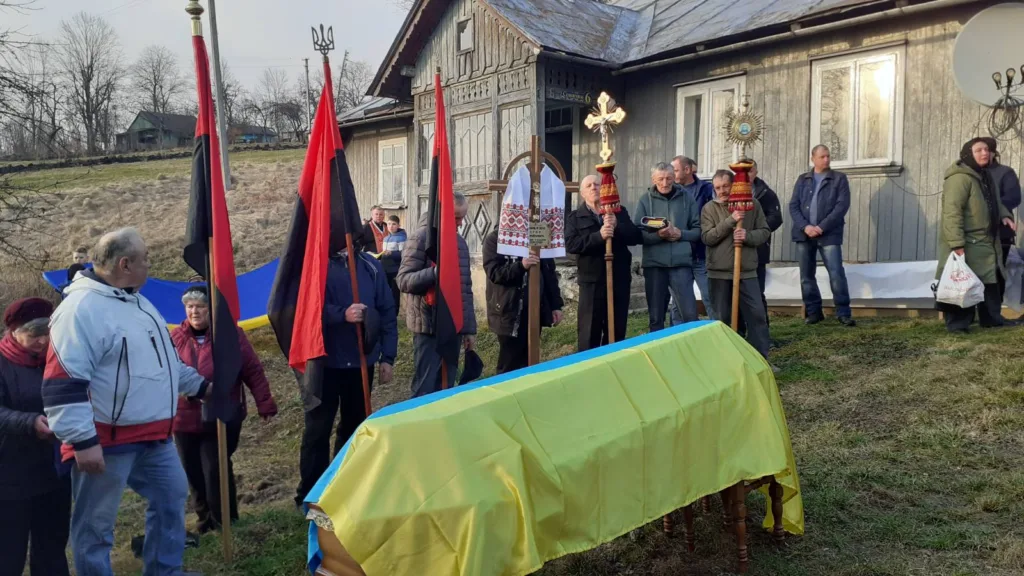 Похоронна процесія з українським прапором біля будинку
