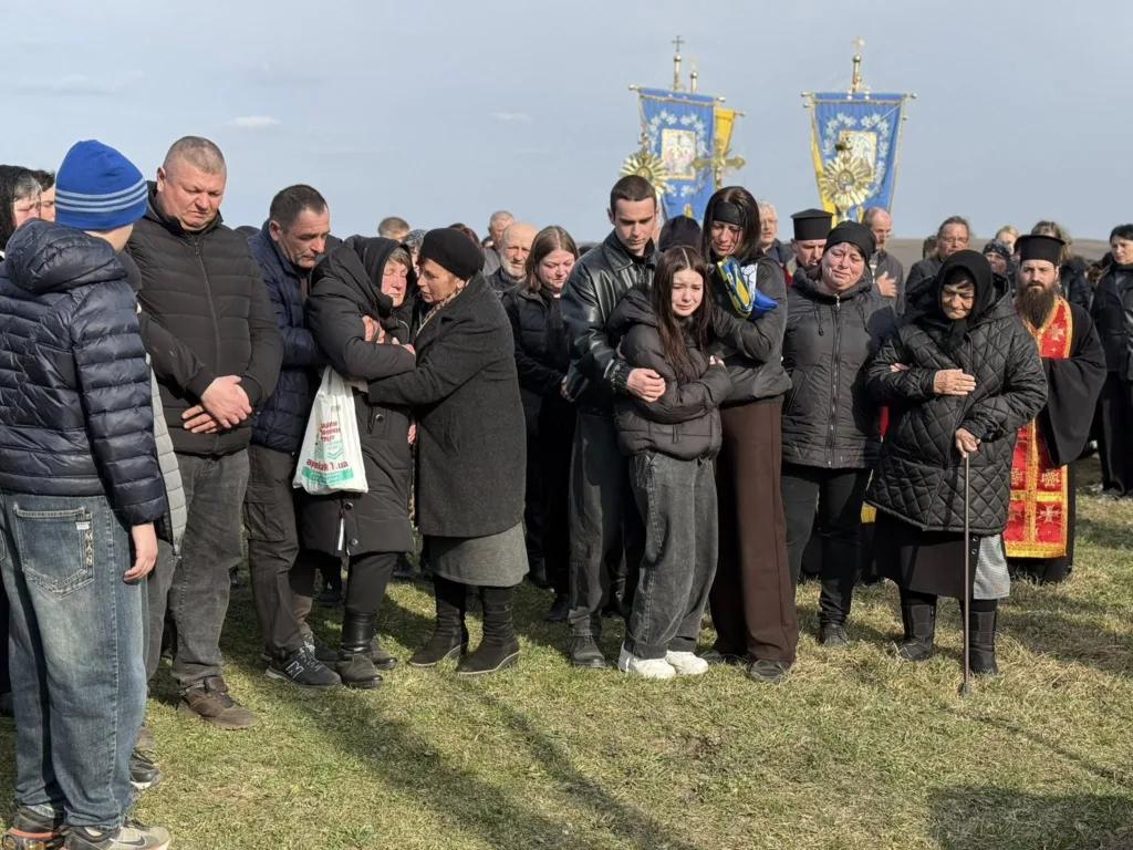 Люди оплакують загиблого на похороні під відкритим небом