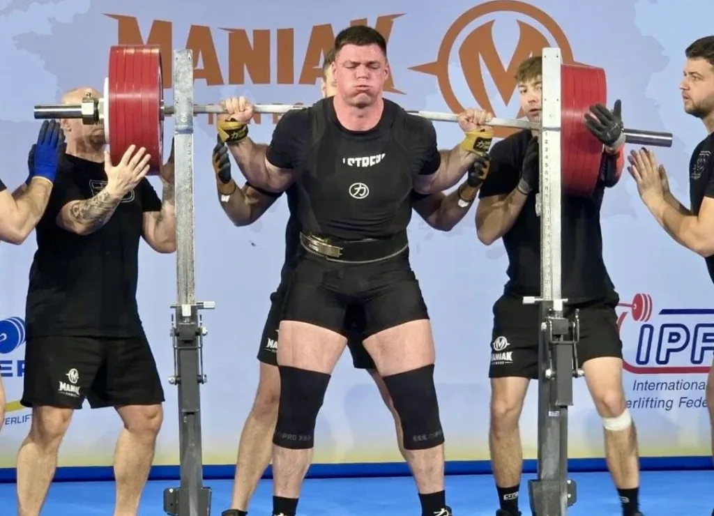 Пауерліфтер виконує присідання зі штангою на змаганнях