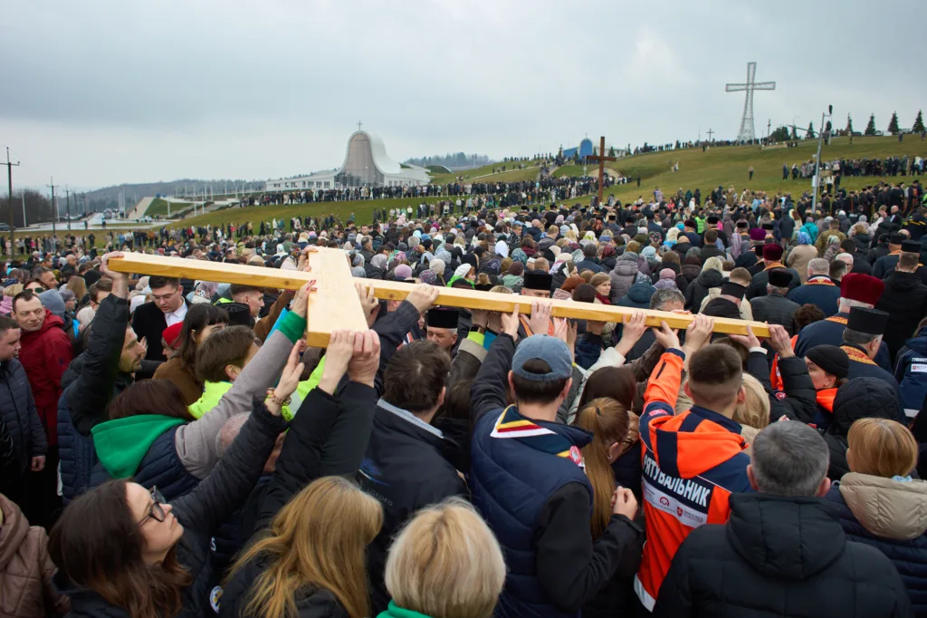 Натовп несе дерев'яний хрест біля церкви