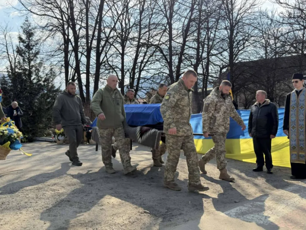 Військові несуть труну під українським прапором