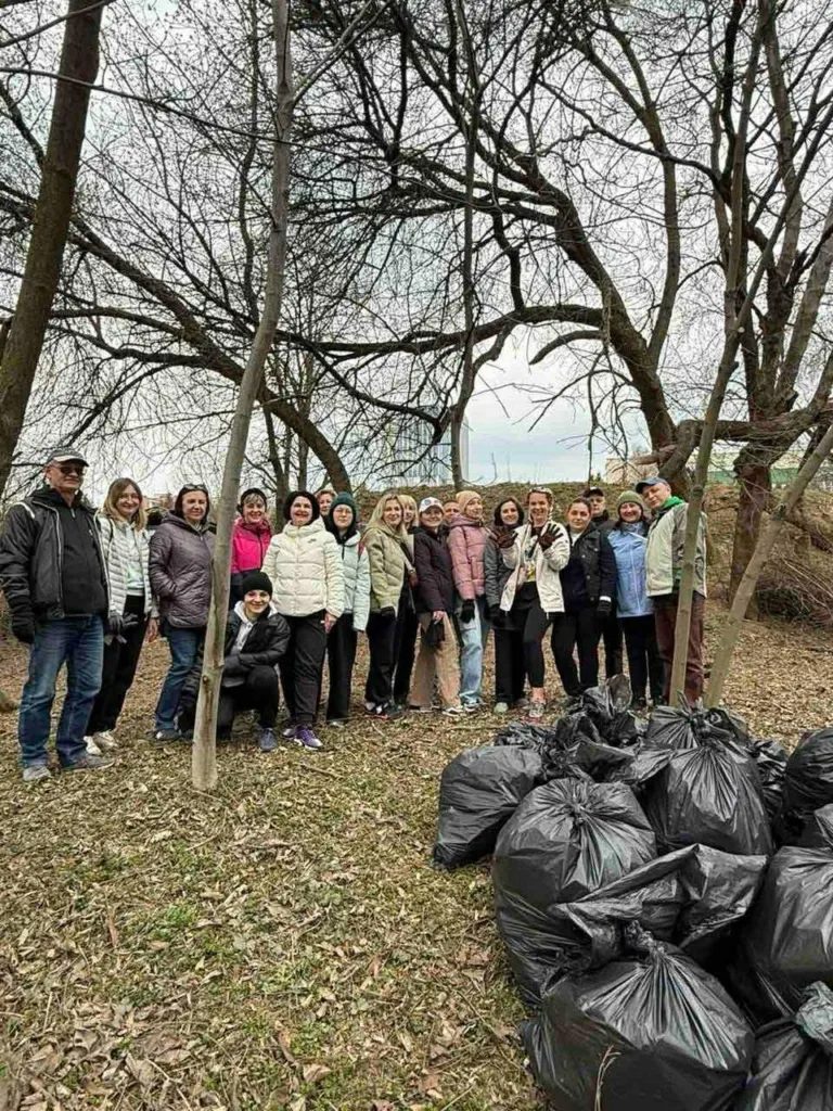 Люди прибирають парк, мішки зі сміттям на землі