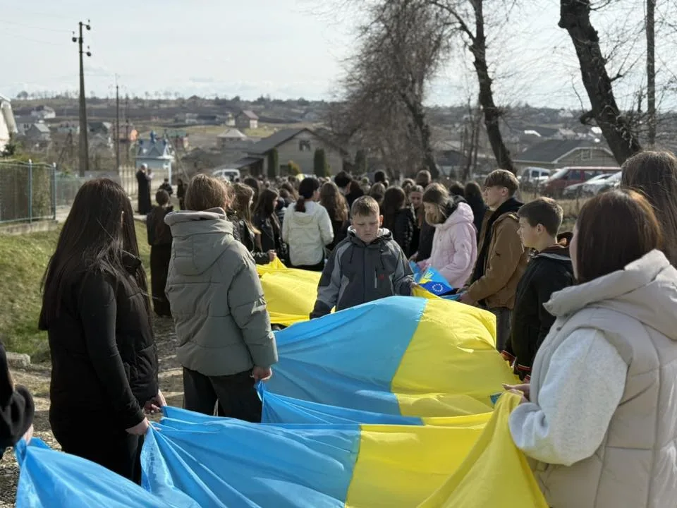 Діти тримають великий прапор України на вулиці