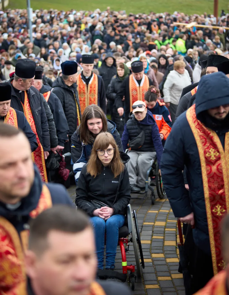 Люди на релігійній ході, жінка у візку спереду