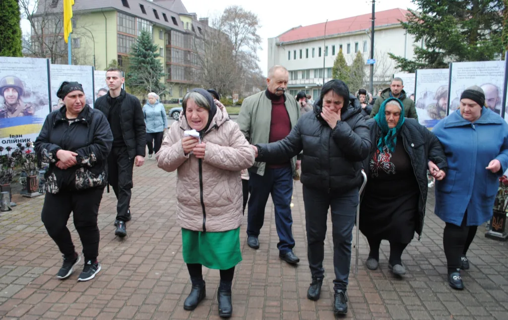 Люди сумують на вулиці під час поминального заходу