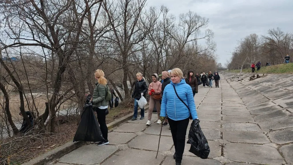Люди прибирають сміття біля річки навесні