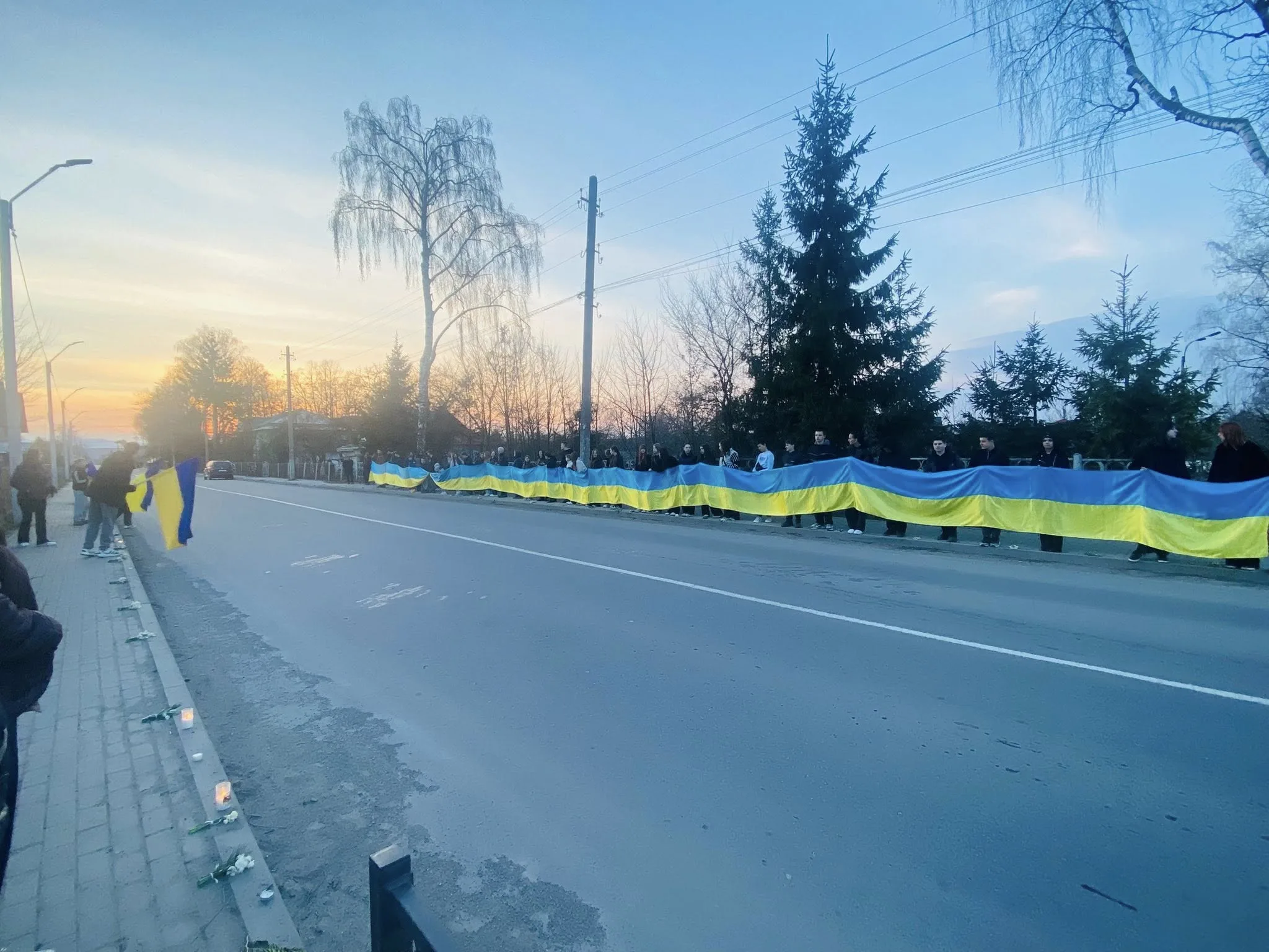 Люди тримають великий прапор України вздовж дороги