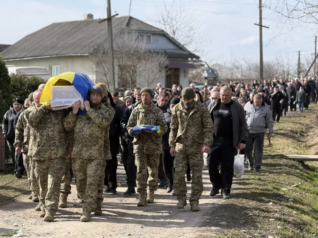Військові несуть труну, накриту прапором України