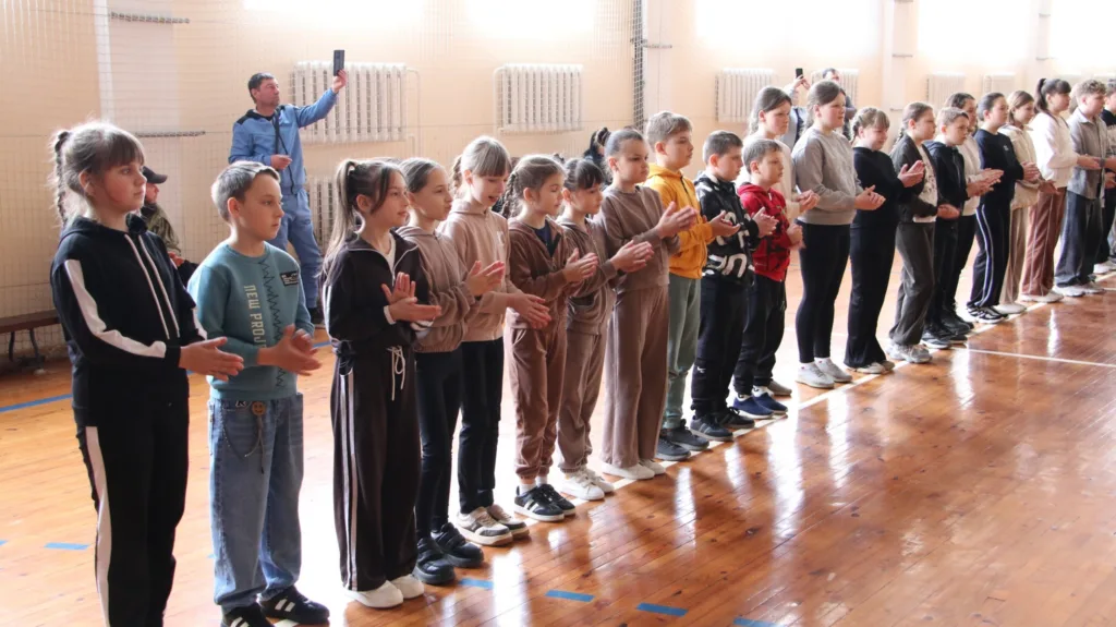 Діти стоять у спортзалі на шкільному заході