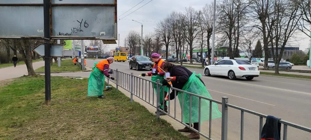 Волонтери фарбують паркан біля дороги