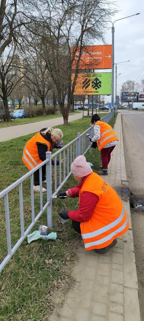 Працівники фарбують паркан біля дороги