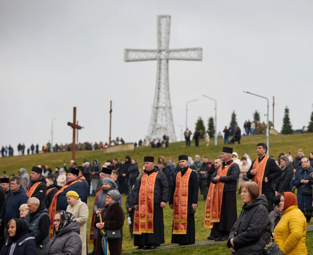 Священики та люди моляться біля великого хреста