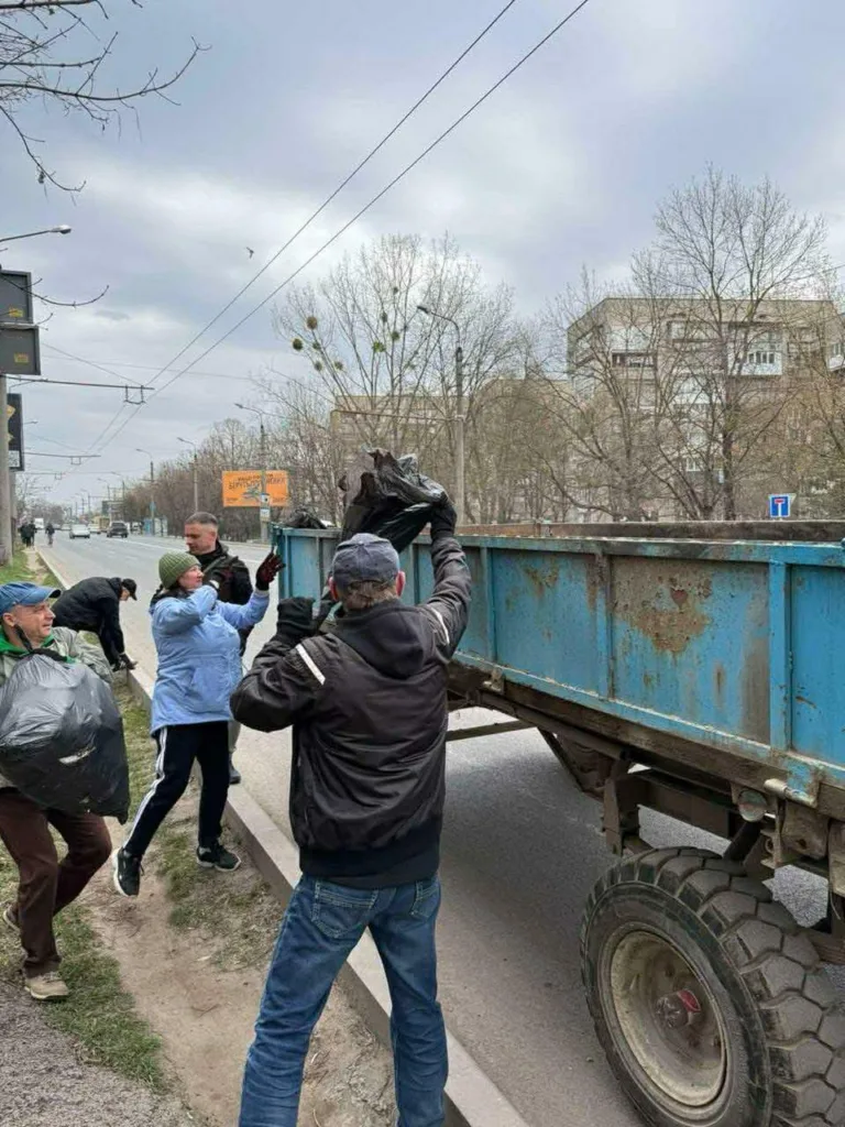 Люди прибирають сміття та завантажують у вантажівку