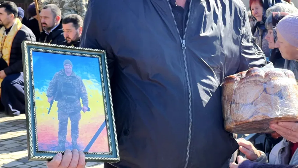 Чоловік тримає фото військового та хліб