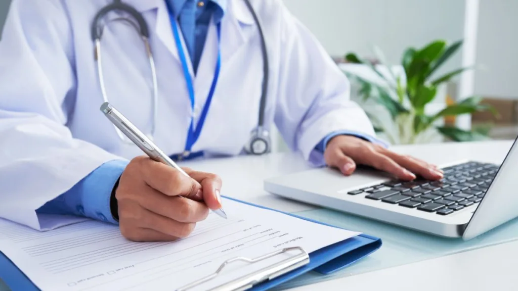 Лікар записує дані біля ноутбука