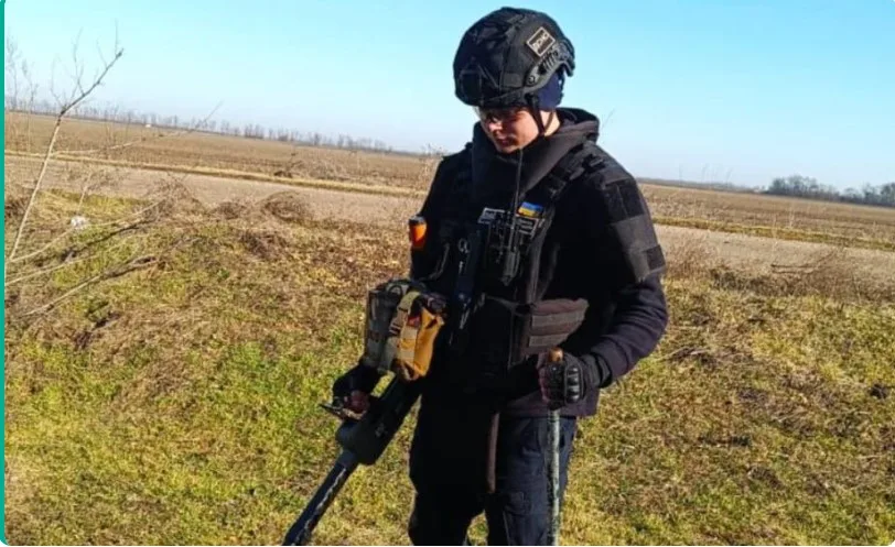 Сапер перевіряє поле металошукачем