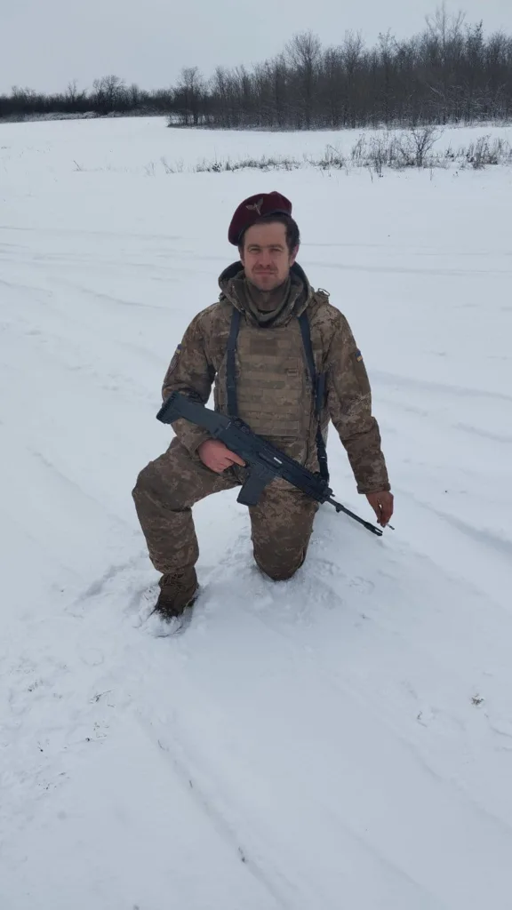 Військовий у камуфляжі на снігу тримає зброю