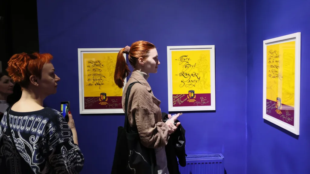 Люди оглядають виставку плакатів у галереї