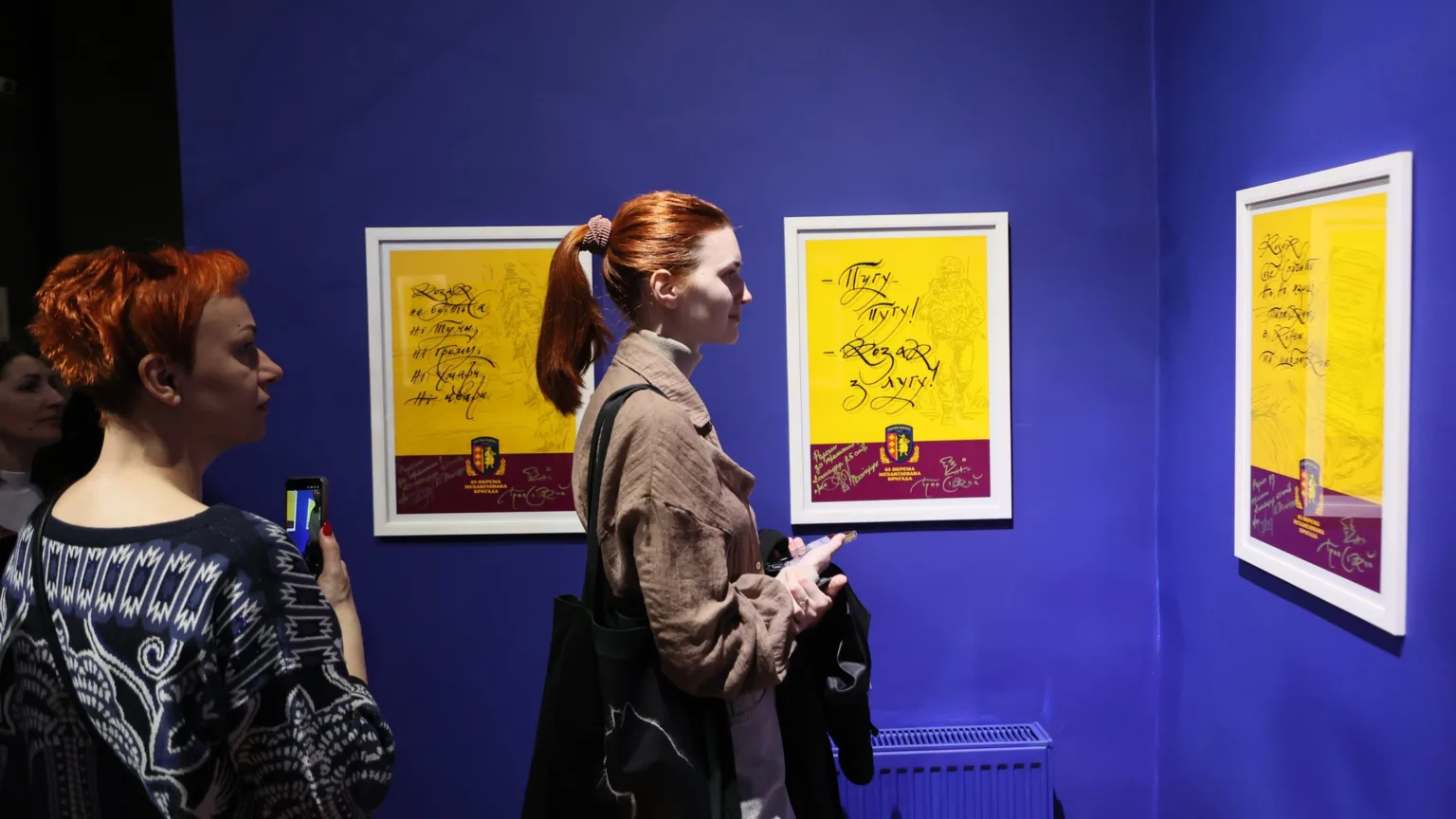 Люди оглядають виставку плакатів у галереї