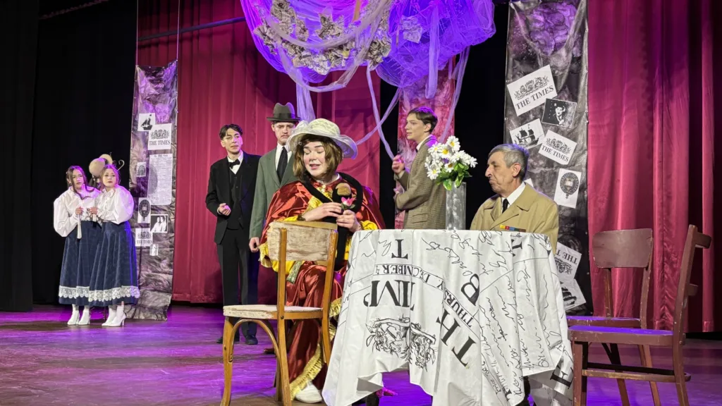 Актори виконують театральну сцену на сцені з декораціями