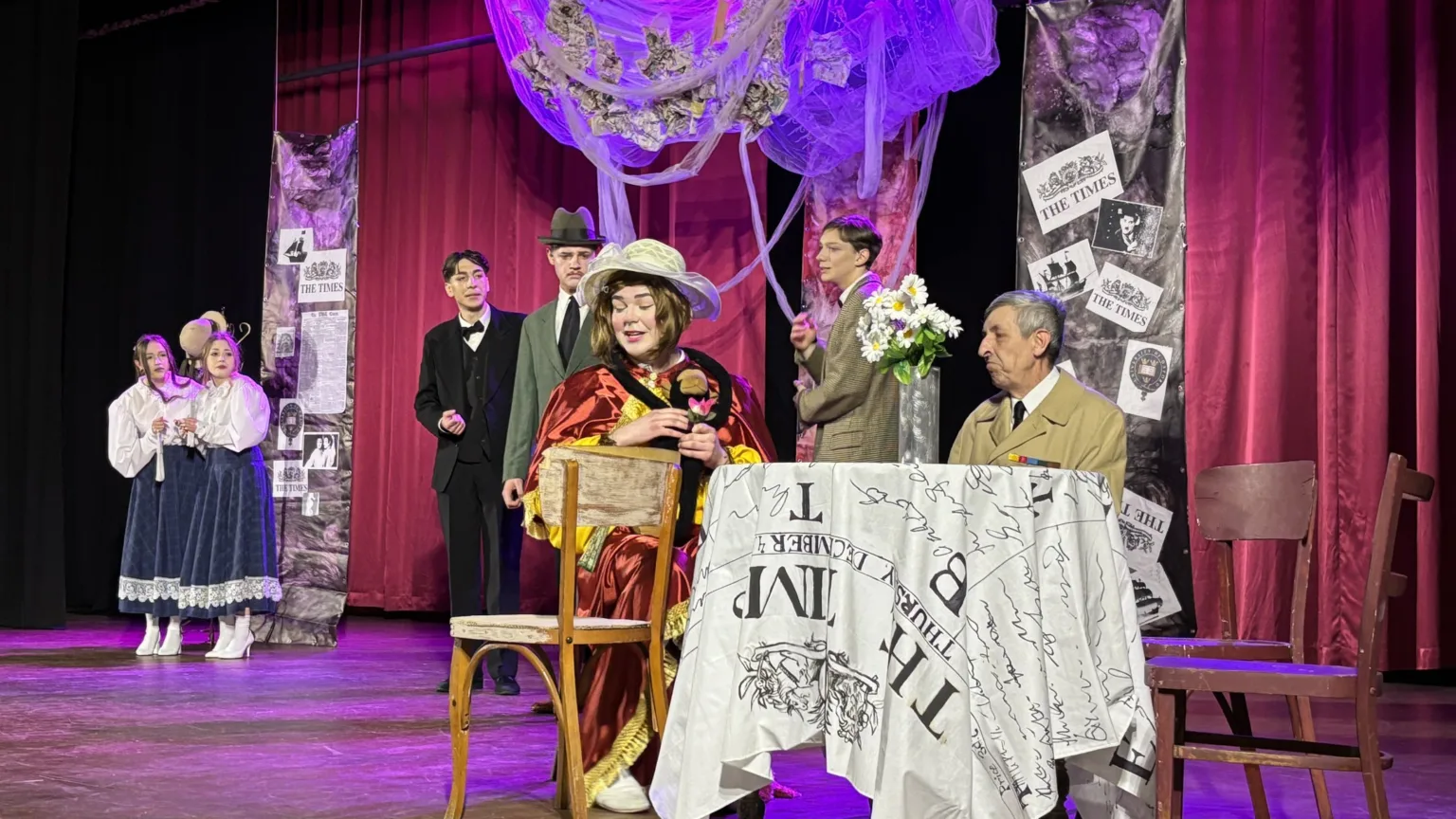 Актори виконують театральну сцену на сцені з декораціями