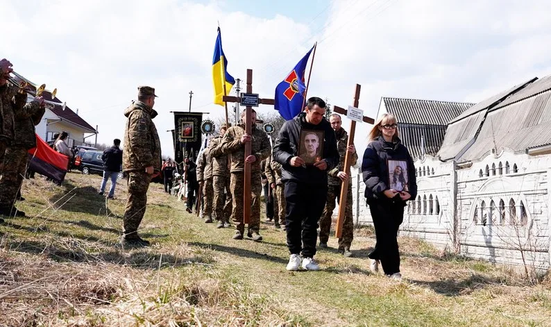 Військові несуть прапори та хрести на похороні