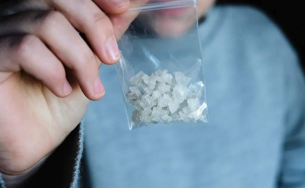 Людина тримає пакет з кристалічною речовиною