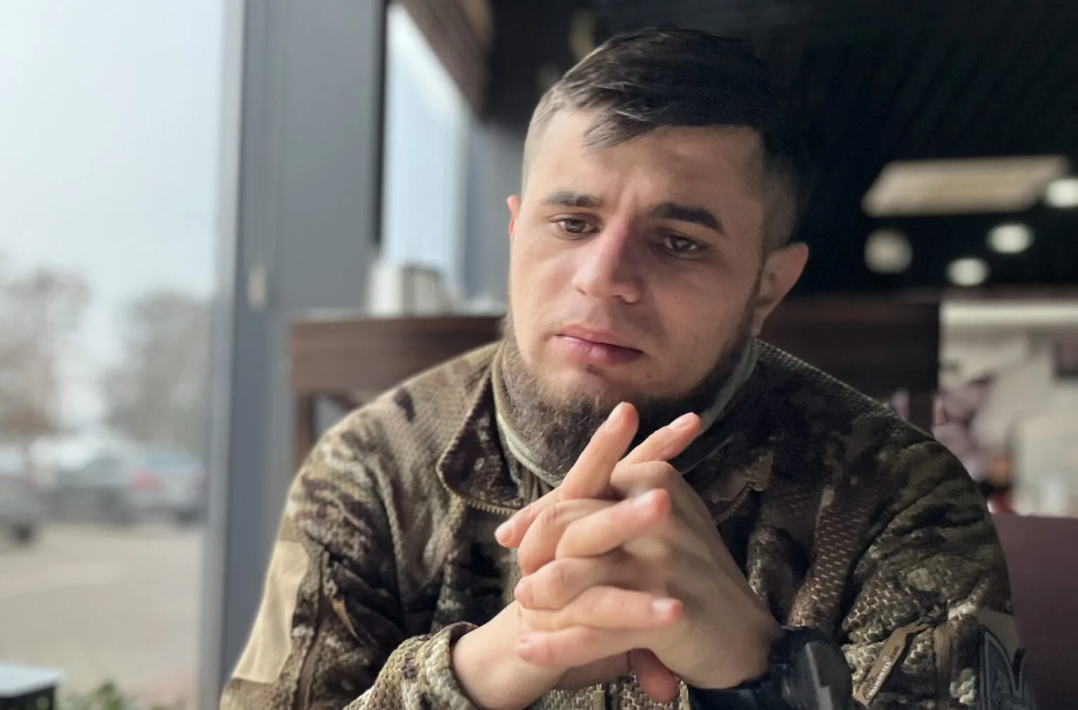 Військовий чоловік сидить у кафе біля вікна