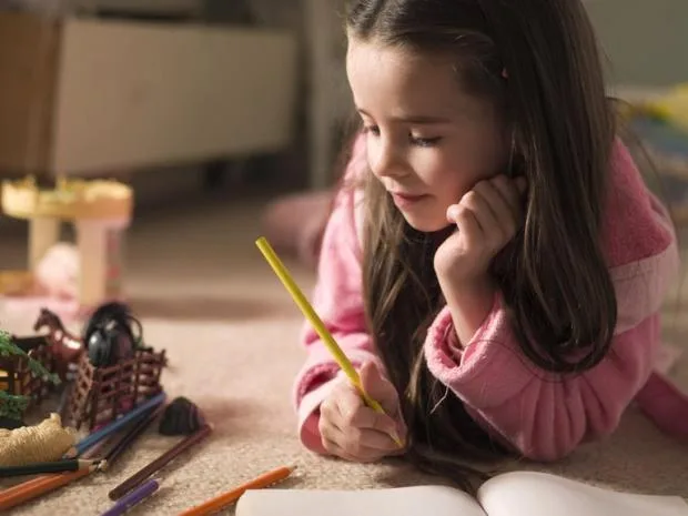 Дівчинка малює кольоровими олівцями вдома