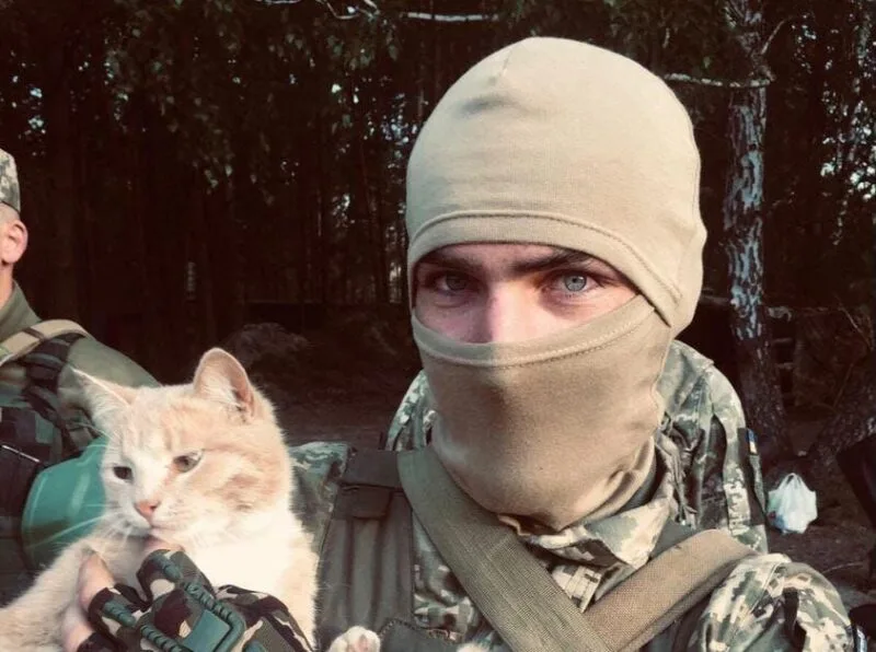 Військовий тримає кота на природі