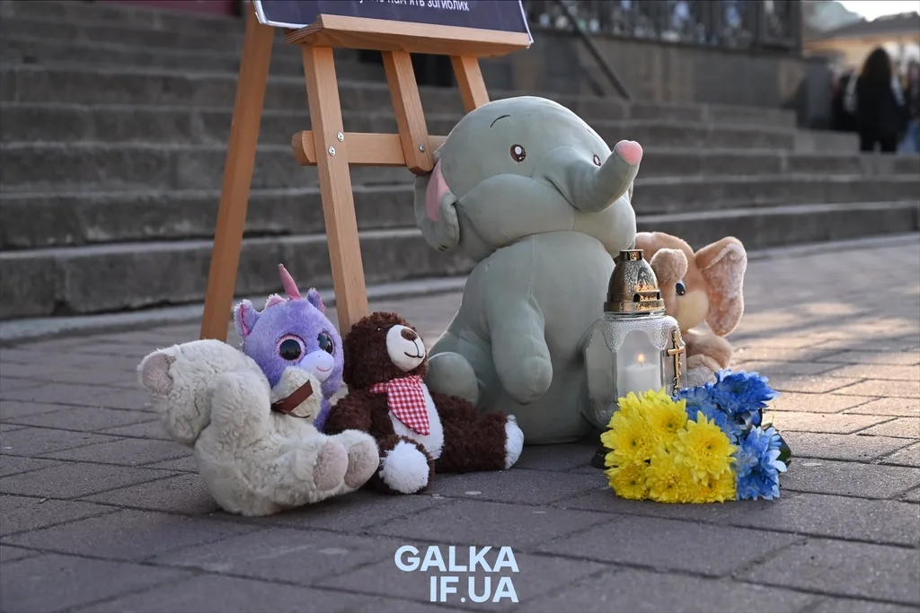 Іграшки, квіти та свічка на меморіалі