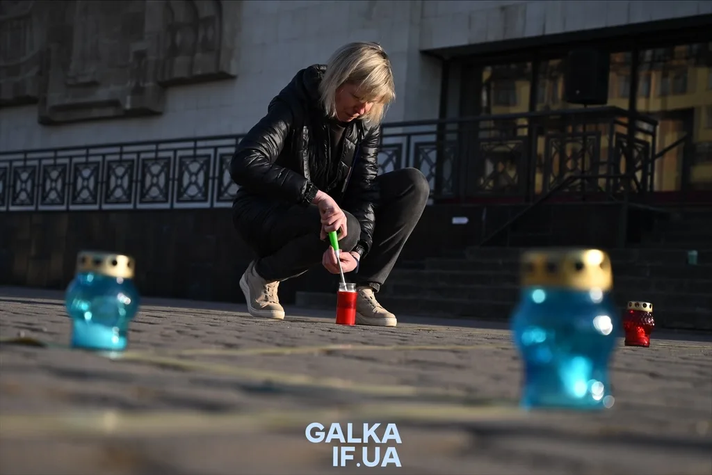 Людина запалює свічку на вулиці