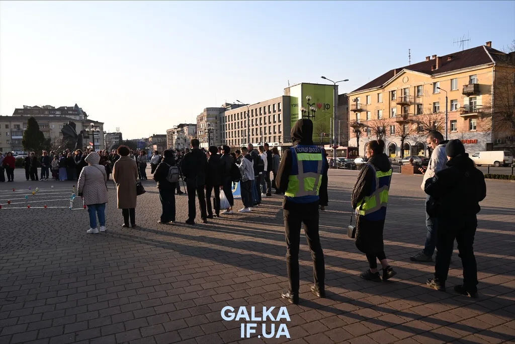 Люди стоять на площі під наглядом поліції