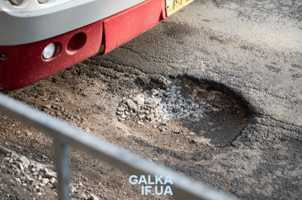 Велика яма на асфальті біля автомобіля