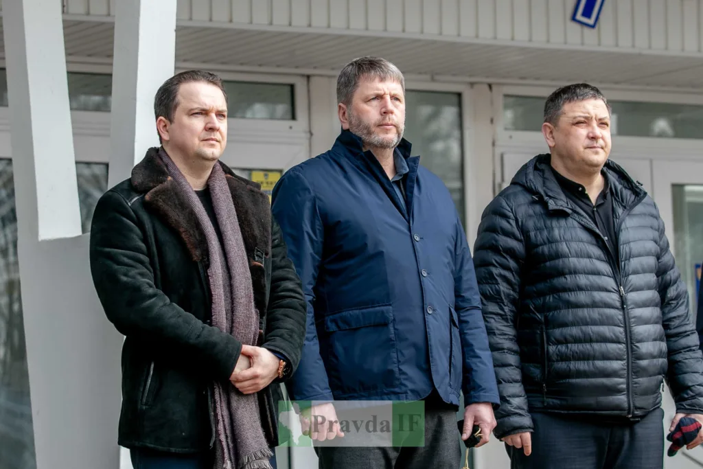 Троє чоловіків стоять перед будівлею