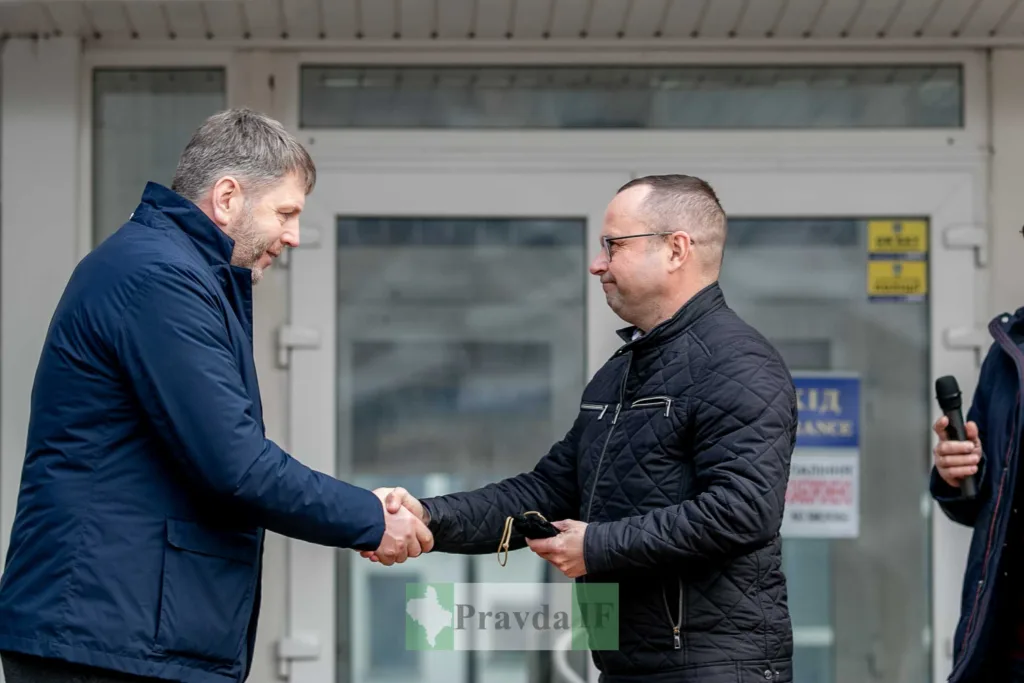 Двоє чоловіків потискають руки перед будівлею