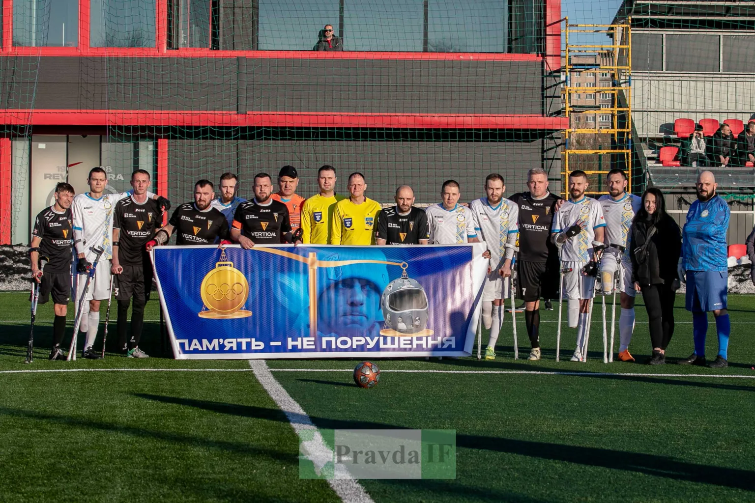 Команди ампфутболістів тримають банер на футбольному полі