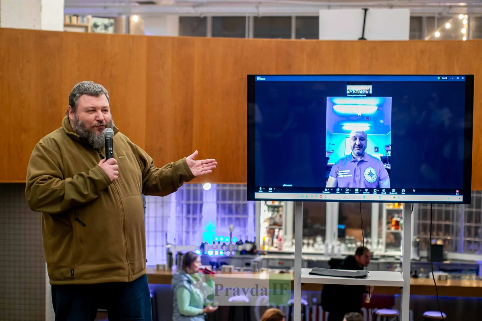 Чоловік виступає біля екрана з відеодзвінком