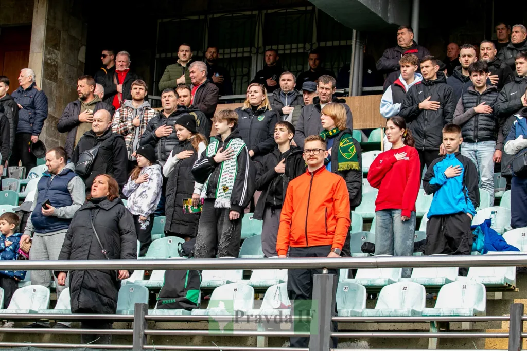 Вболівальники стоять на трибуні під час гімну