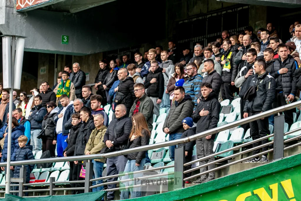 Вболівальники стоять на трибуні футбольного стадіону