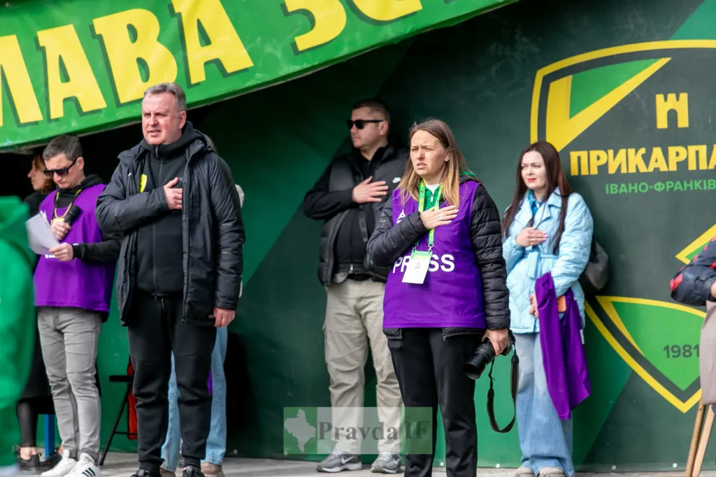 Люди стоять з рукою на серці на стадіоні