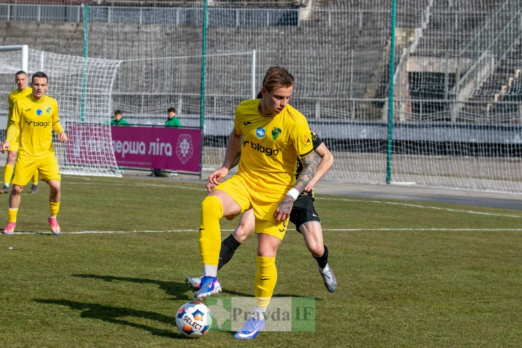 Футболіст у жовтій формі контролює м'яч на полі