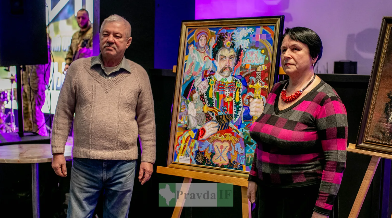 Двоє людей біля яскравої картини на виставці