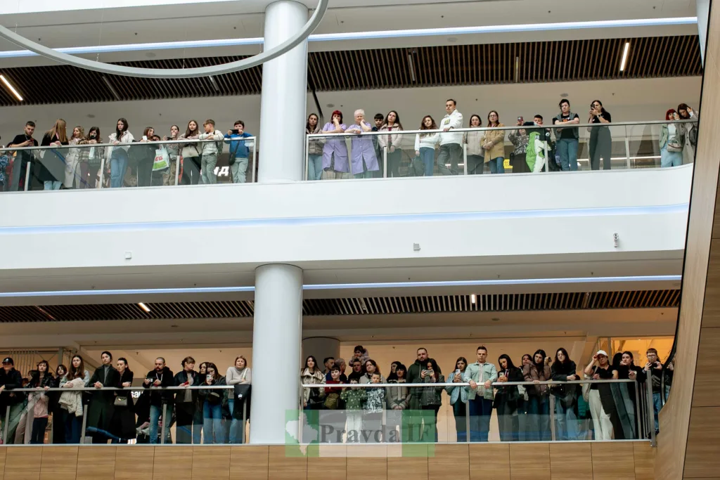 Люди стоять на балконах торгового центру