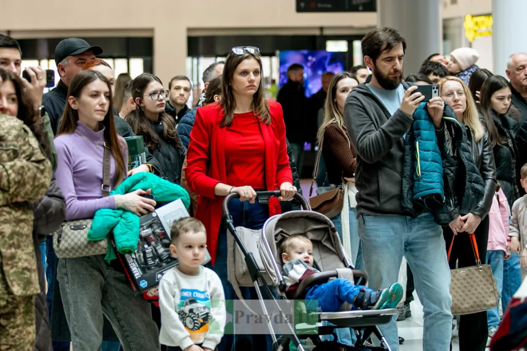 Люди з дітьми на громадському заході в приміщенні