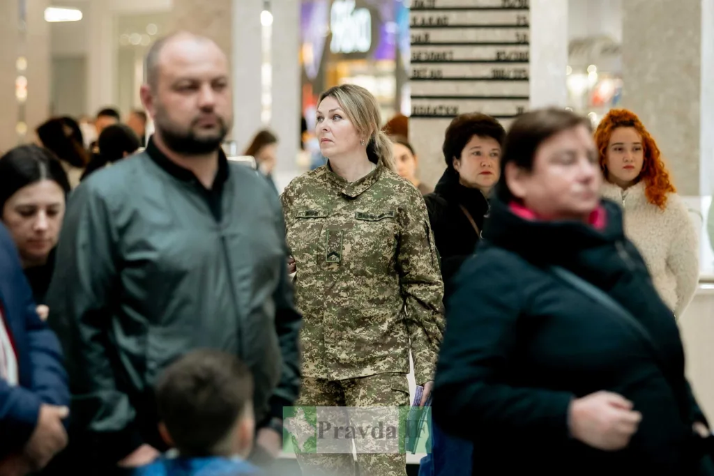 Жінка у військовій формі серед людей у місті