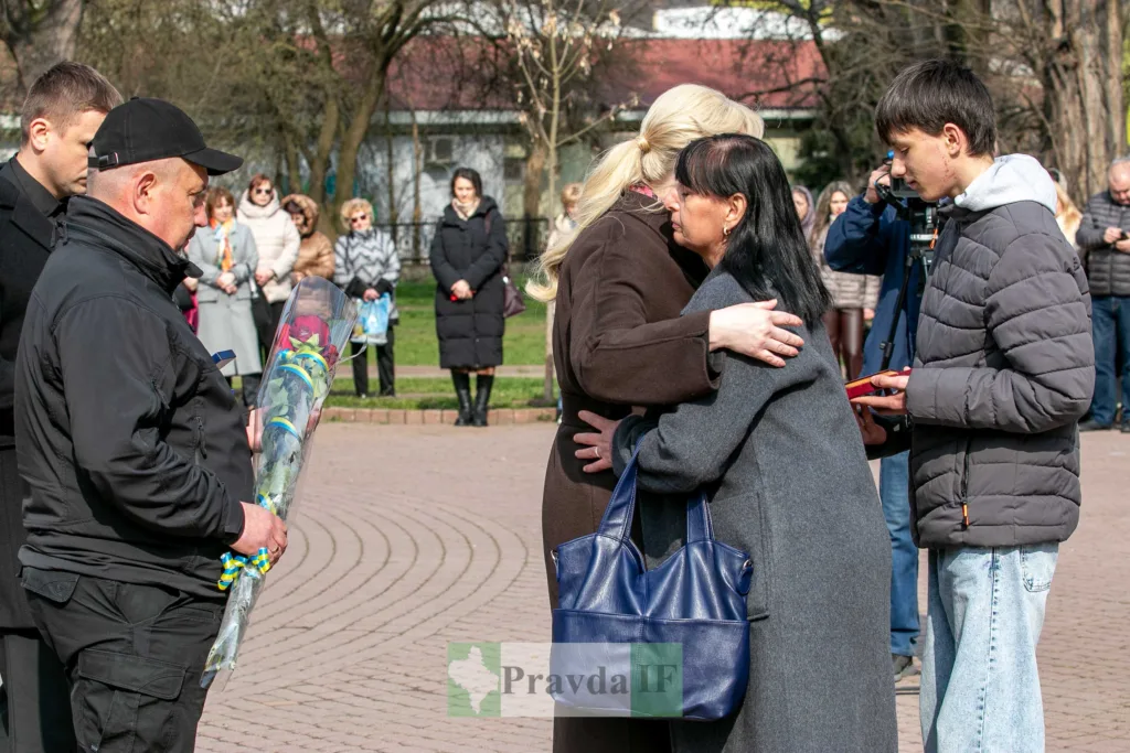Люди на церемонії пам’яті з квітами в парку
