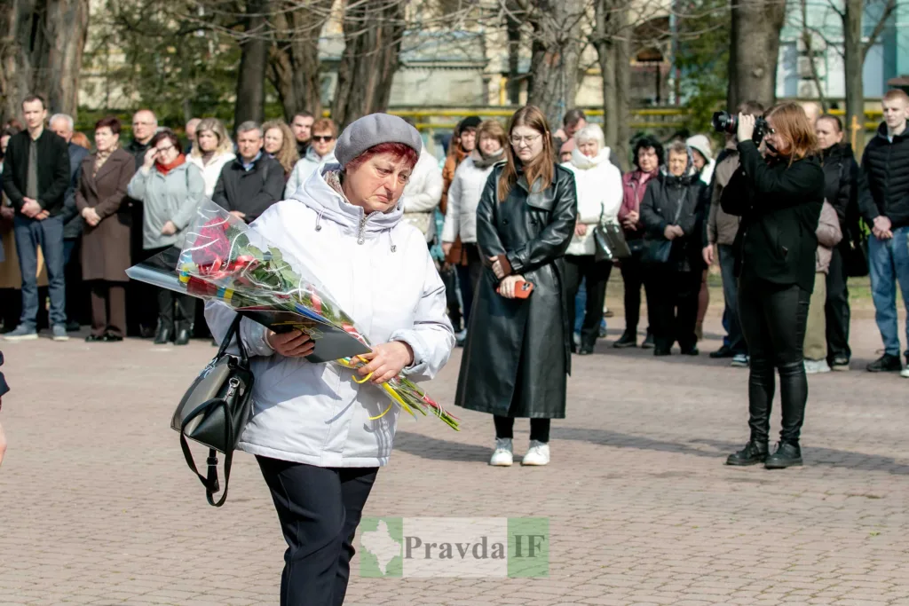 Жінка з квітами на меморіальному заході