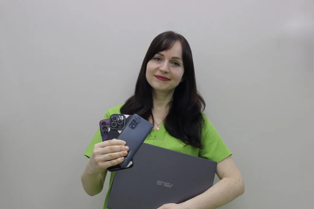 Жінка тримає ноутбук та кілька смартфонів